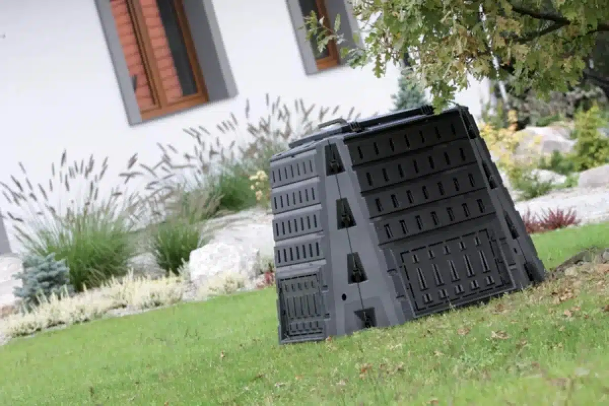 Černý plastový zahradní kompostér na trávníku u domu