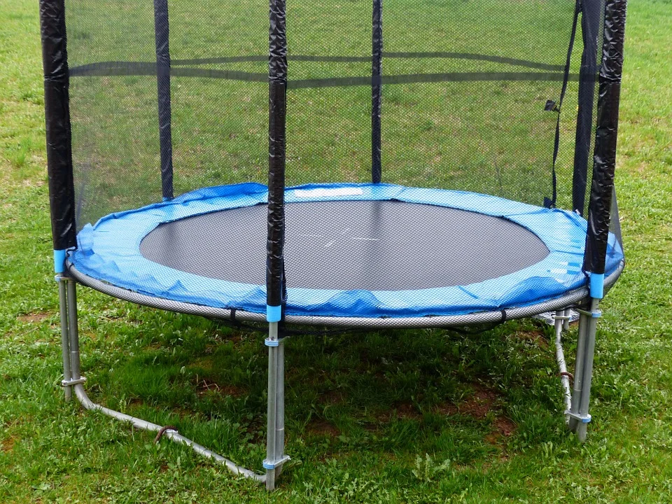 Trampolína s ochrannou sítí na zahradě rodinného domu